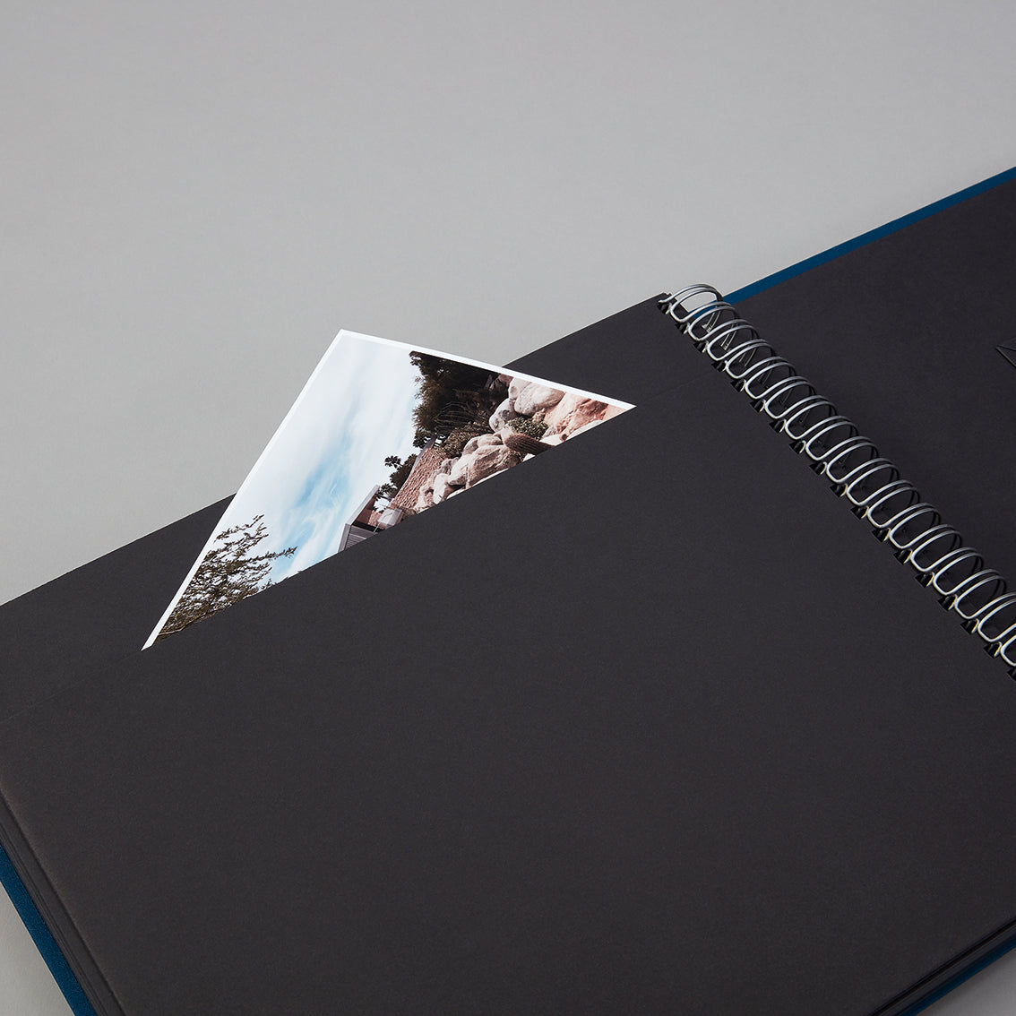 Black spiral-bound photo album with a photo of a mountain landscape on top